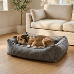 Gray corduroy orthopaedic pet bed with cushioned bolsters and textured fabric; dog lying inside