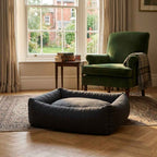 Dark gray round pet nest bed with thick high walls, empty in a living room setting