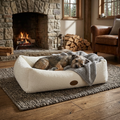 Cream bouclé pet nest bed with three dogs lying down and gray throw