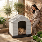 Raised plastic dog kennel with ramp, white arched door; dog resting on beige cushion.